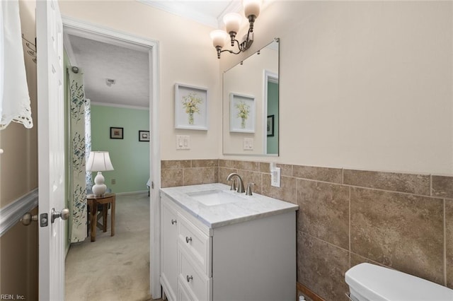 half bathroom featuring toilet, tile walls, vanity, and ornamental molding