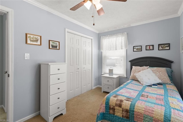 carpeted bedroom featuring a ceiling fan, baseboards, ornamental molding, a closet, and a textured ceiling