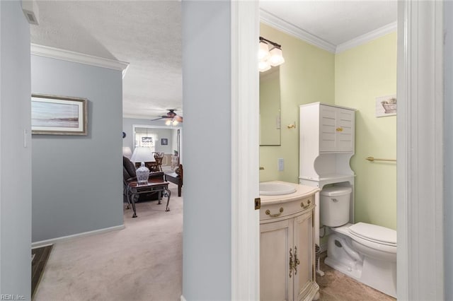 half bathroom with toilet, vanity, ornamental molding, a textured ceiling, and a ceiling fan