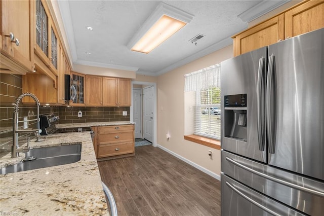 kitchen with decorative backsplash, a sink, stainless steel appliances, crown molding, and glass insert cabinets