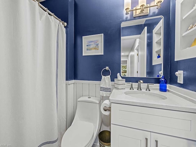 full bathroom featuring wainscoting, vanity, and toilet