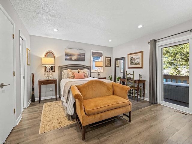 bedroom featuring visible vents, wood finished floors, a textured ceiling, and access to exterior