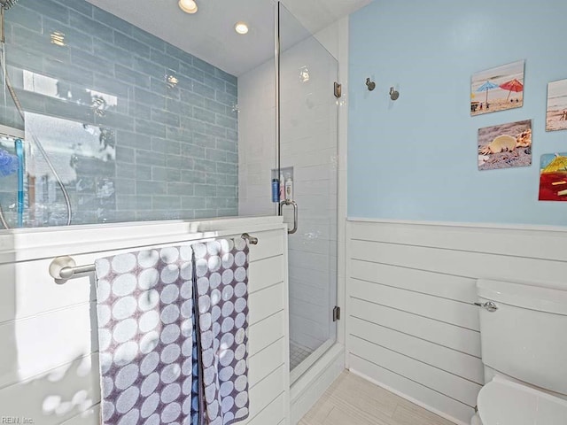 full bath featuring a wainscoted wall, a shower stall, and toilet