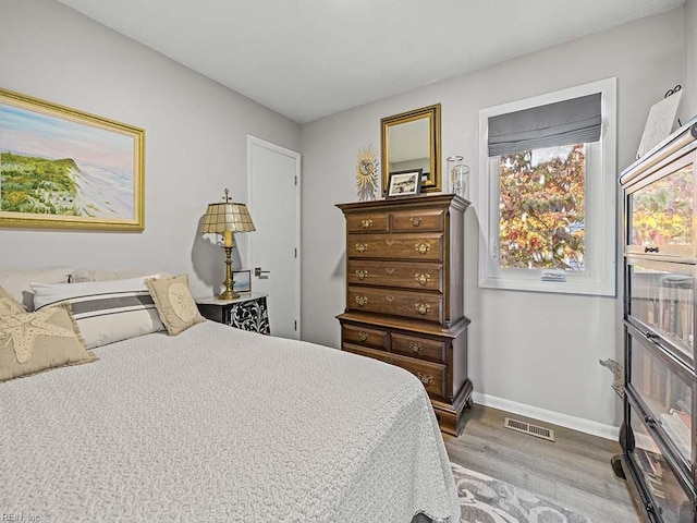 bedroom featuring visible vents, baseboards, and wood finished floors