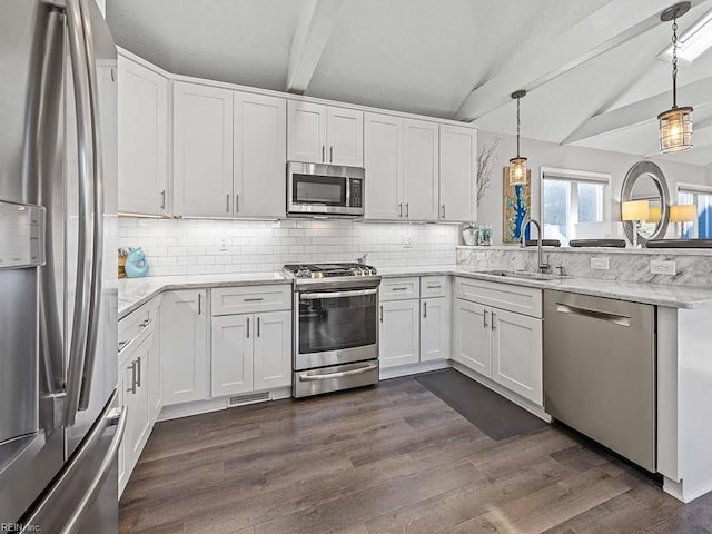 kitchen with dark wood-style floors, lofted ceiling with beams, a peninsula, a sink, and stainless steel appliances