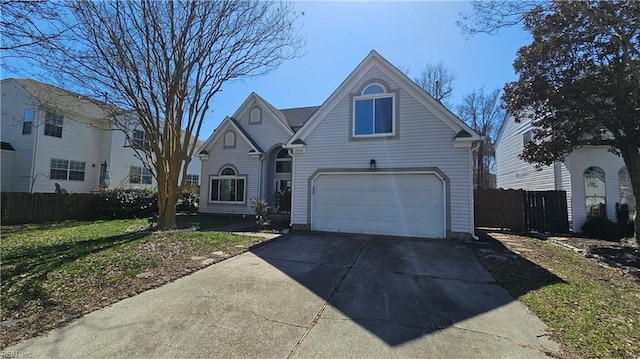 traditional-style home featuring a front lawn, an attached garage, fence, and driveway