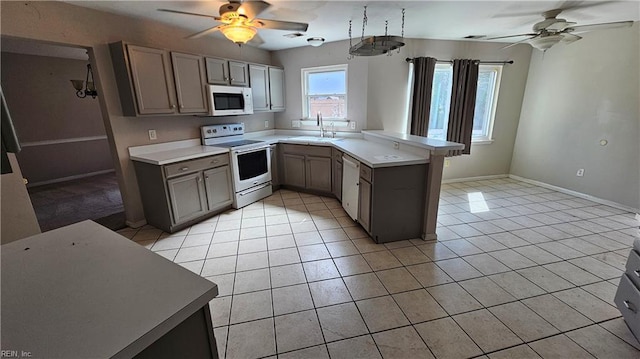 kitchen with white appliances, a peninsula, gray cabinets, and a sink