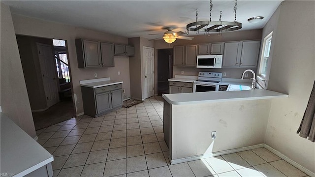 kitchen with white appliances, light tile patterned floors, gray cabinets, and a sink