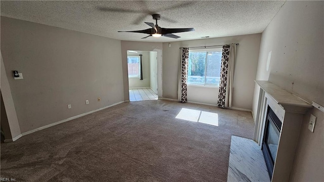 unfurnished living room with a glass covered fireplace, a textured ceiling, a ceiling fan, and carpet floors