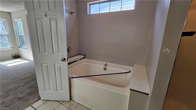 bathroom featuring a textured ceiling, a bath, and tile patterned flooring