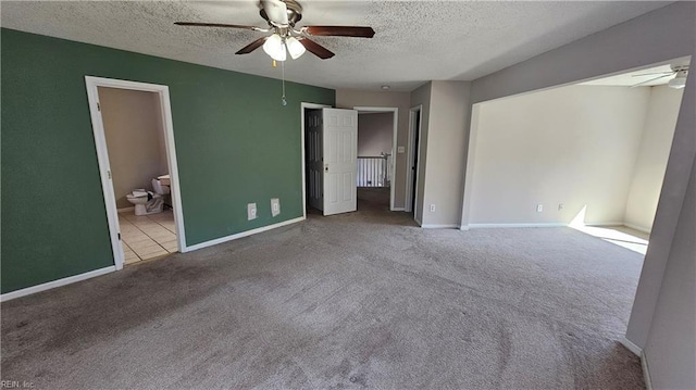 unfurnished bedroom with connected bathroom, a textured ceiling, baseboards, and carpet floors