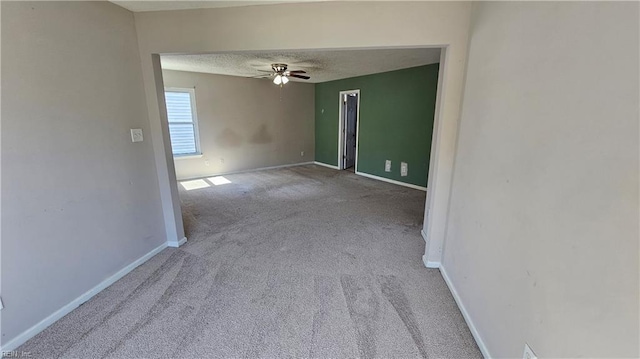 carpeted spare room with ceiling fan, baseboards, and a textured ceiling