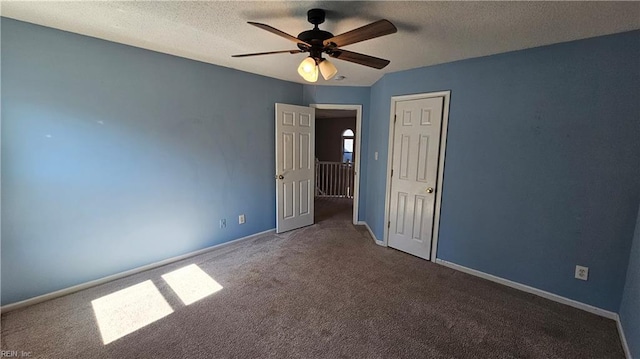 unfurnished bedroom with baseboards, a textured ceiling, carpet, and a ceiling fan