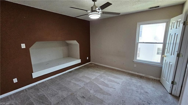 unfurnished bedroom featuring multiple windows, visible vents, carpet floors, and a textured ceiling