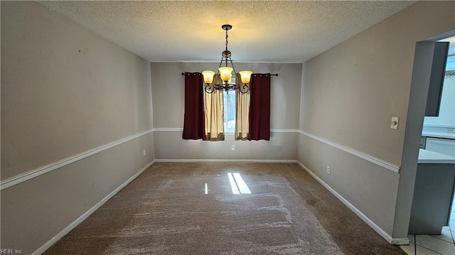 carpeted spare room with a textured ceiling, baseboards, and a chandelier