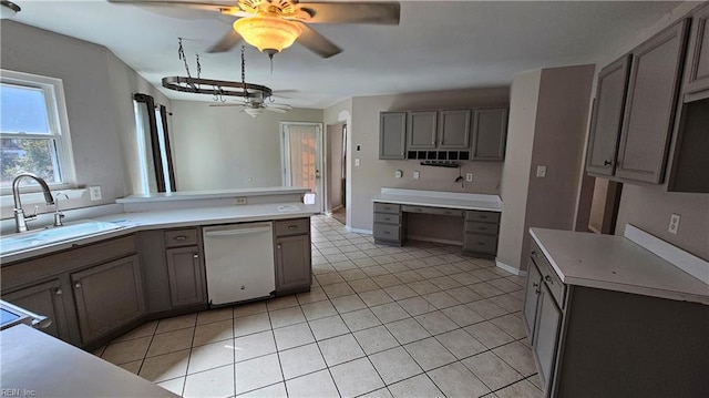 kitchen featuring dishwashing machine, gray cabinetry, light countertops, and a sink