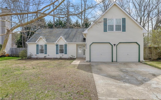 traditional-style house with a front lawn, concrete driveway, an attached garage, and fence