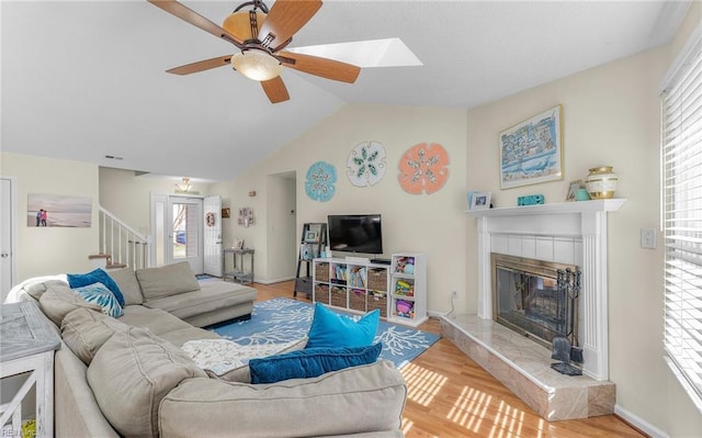 living area featuring wood finished floors, stairway, plenty of natural light, and a fireplace