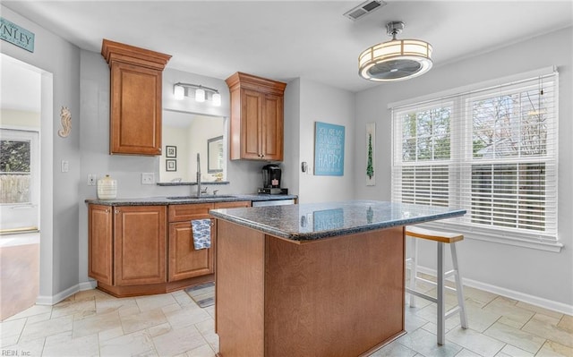 kitchen featuring a wealth of natural light, visible vents, brown cabinets, and a sink