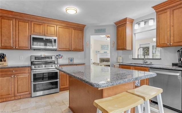 kitchen featuring brown cabinetry, stainless steel appliances, and a sink