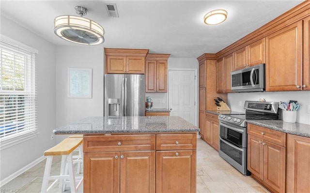 kitchen with a kitchen island, visible vents, stone countertops, and stainless steel appliances