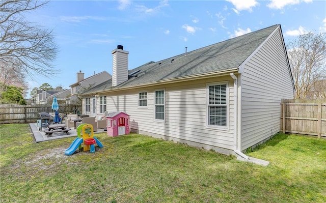 rear view of property featuring a patio area, a yard, a fenced backyard, and a chimney