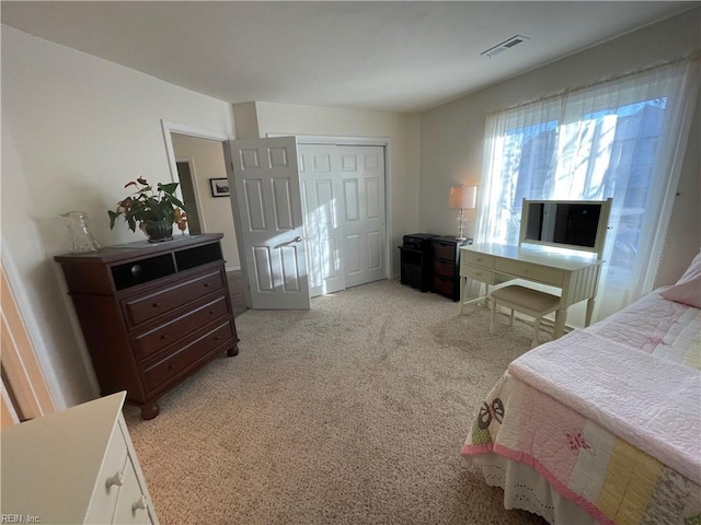 bedroom with visible vents, a closet, and light carpet