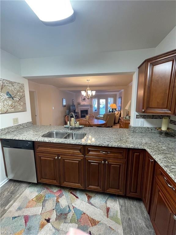 kitchen with a sink, light wood-style floors, dishwasher, and a peninsula