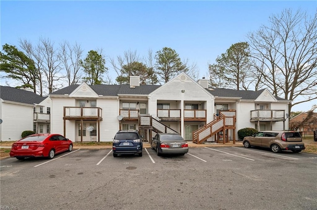 view of property with stairway and uncovered parking