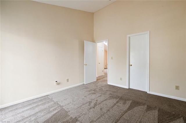 unfurnished bedroom with baseboards, a high ceiling, and carpet flooring