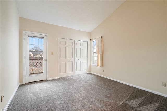 unfurnished bedroom featuring carpet flooring, vaulted ceiling, multiple windows, and baseboards