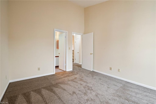 spare room featuring baseboards, carpet, and a high ceiling