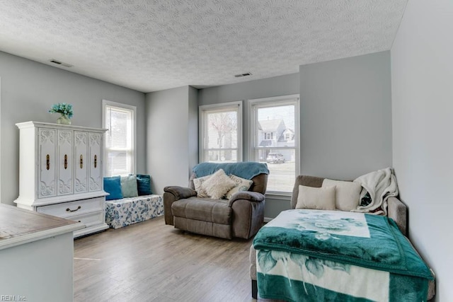 bedroom with light wood-type flooring, visible vents, and a textured ceiling