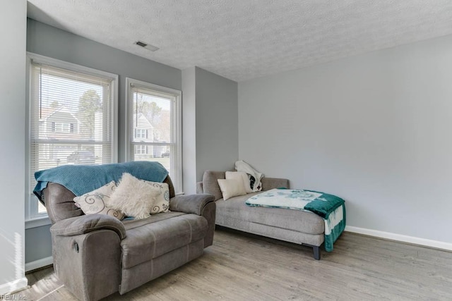 bedroom featuring visible vents, baseboards, a textured ceiling, and light wood finished floors