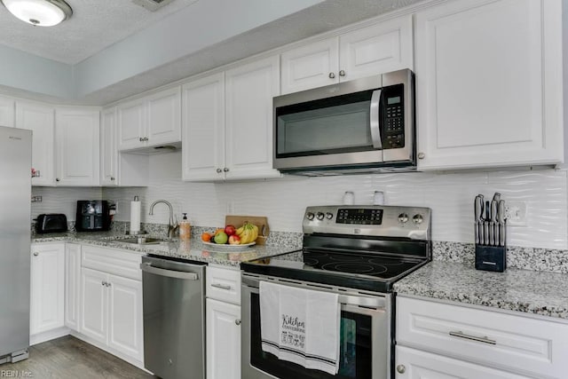 kitchen featuring decorative backsplash, appliances with stainless steel finishes, white cabinetry, and a sink