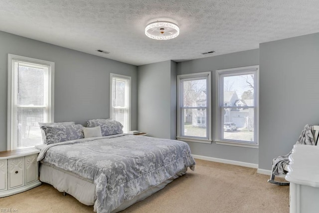 bedroom featuring visible vents, baseboards, light colored carpet, and a textured ceiling