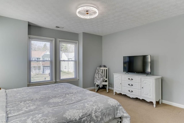 bedroom with a textured ceiling, light colored carpet, visible vents, and baseboards