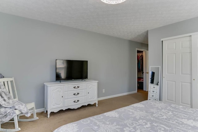 bedroom featuring carpet, baseboards, a closet, and a textured ceiling