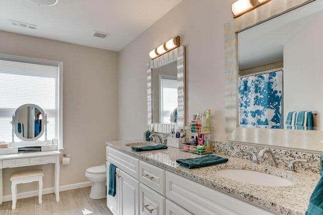 bathroom featuring visible vents, toilet, and a sink