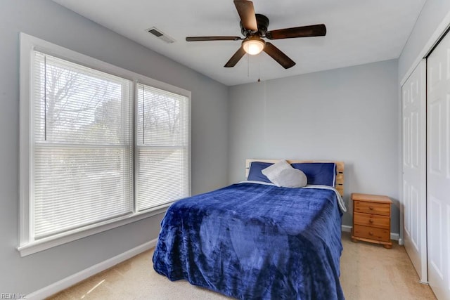 carpeted bedroom with a closet, visible vents, a ceiling fan, and baseboards