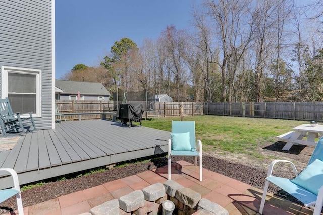 view of patio featuring a wooden deck, a trampoline, a grill, and a fenced backyard