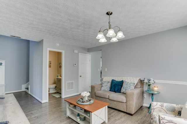 living area featuring baseboards, wood finished floors, visible vents, and a chandelier