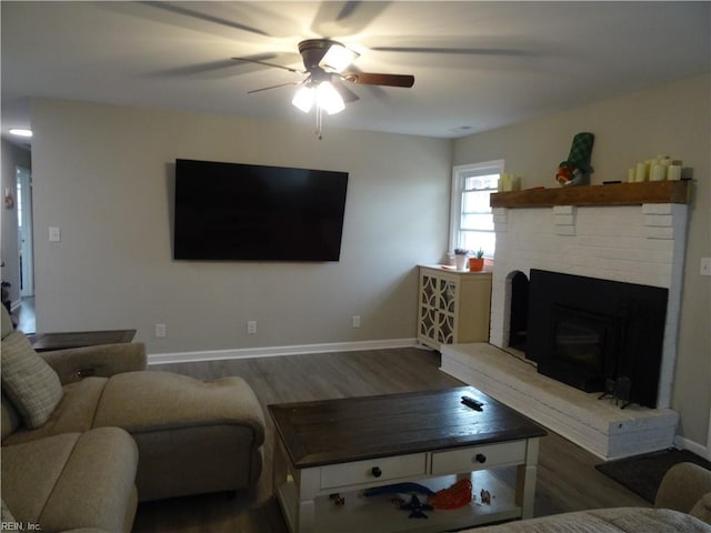 living room with baseboards, a brick fireplace, and wood finished floors