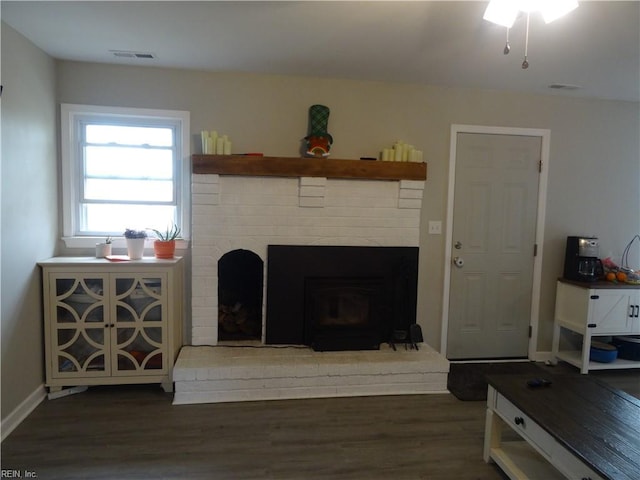 living area with visible vents, a fireplace, baseboards, and wood finished floors