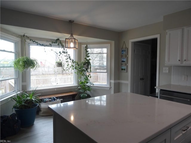 kitchen featuring a healthy amount of sunlight, pendant lighting, white cabinetry, and wood finished floors