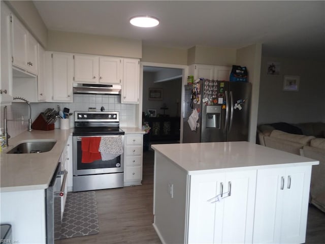 kitchen with a sink, under cabinet range hood, appliances with stainless steel finishes, white cabinetry, and backsplash