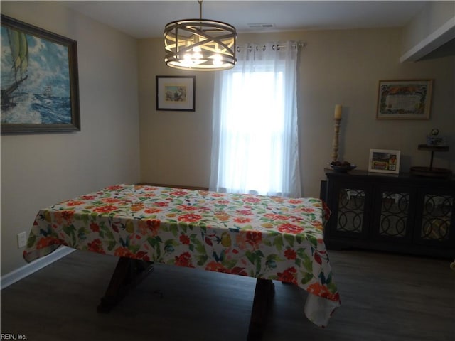 dining room featuring a notable chandelier, wood finished floors, visible vents, and baseboards