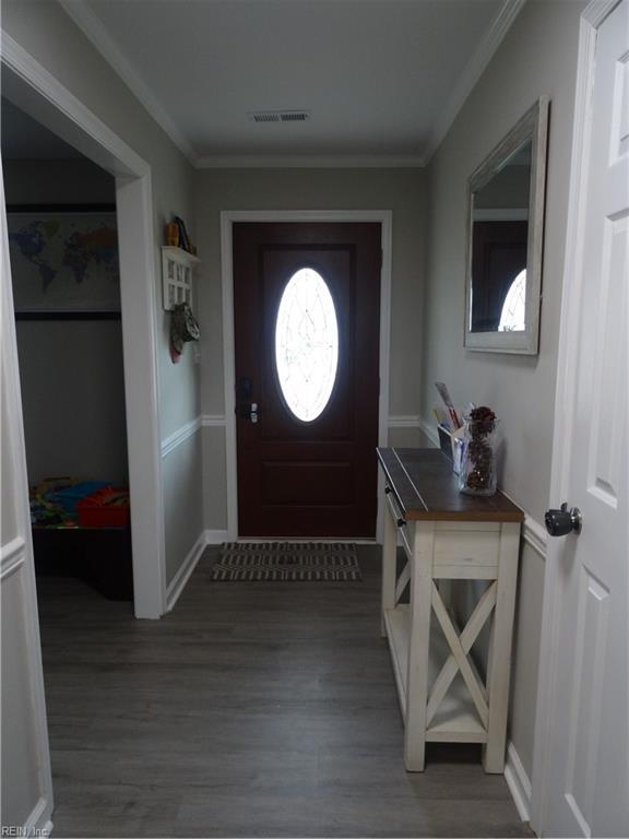 entryway featuring visible vents, wood finished floors, baseboards, and ornamental molding