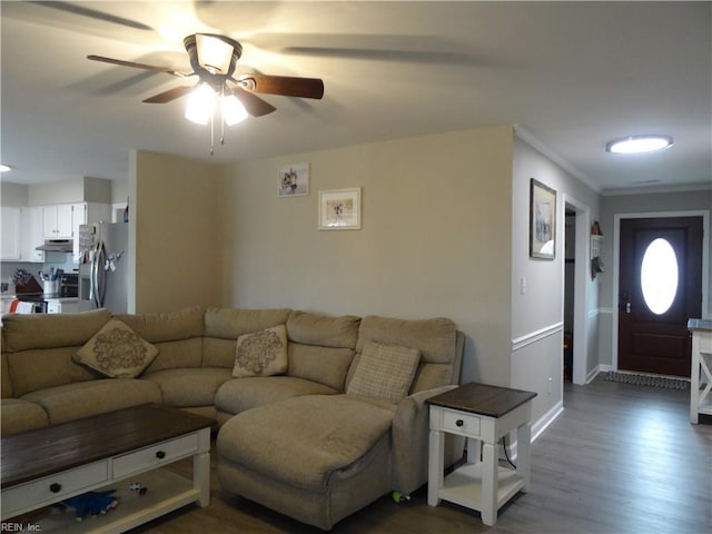 living area with baseboards, dark wood-type flooring, ceiling fan, and crown molding