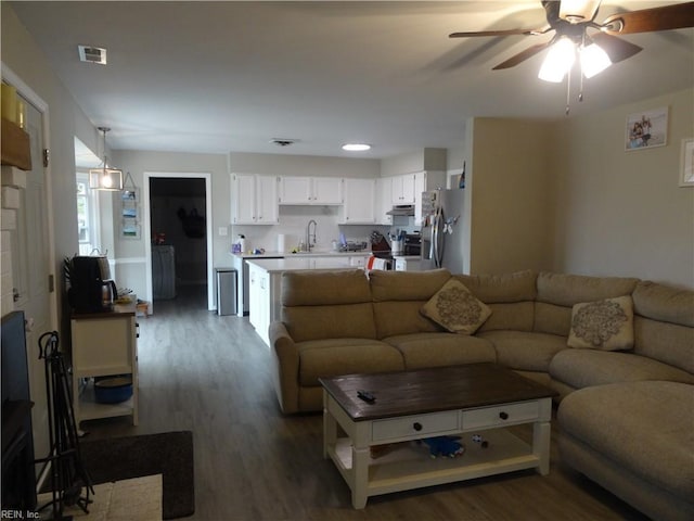 living area featuring visible vents, a ceiling fan, and wood finished floors